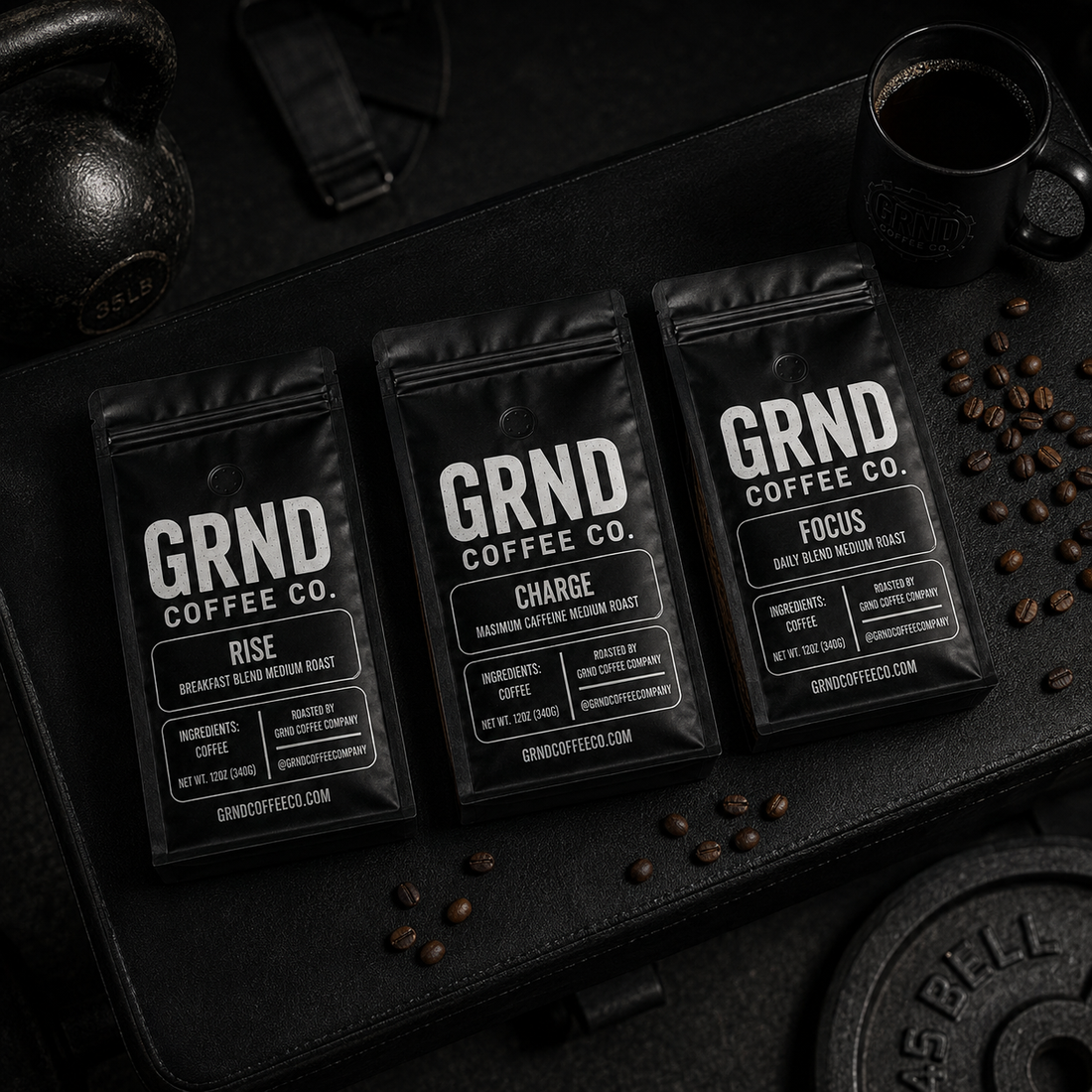 GRND RISE, CHARGE, and FOCUS coffee bags arranged on a black training bench